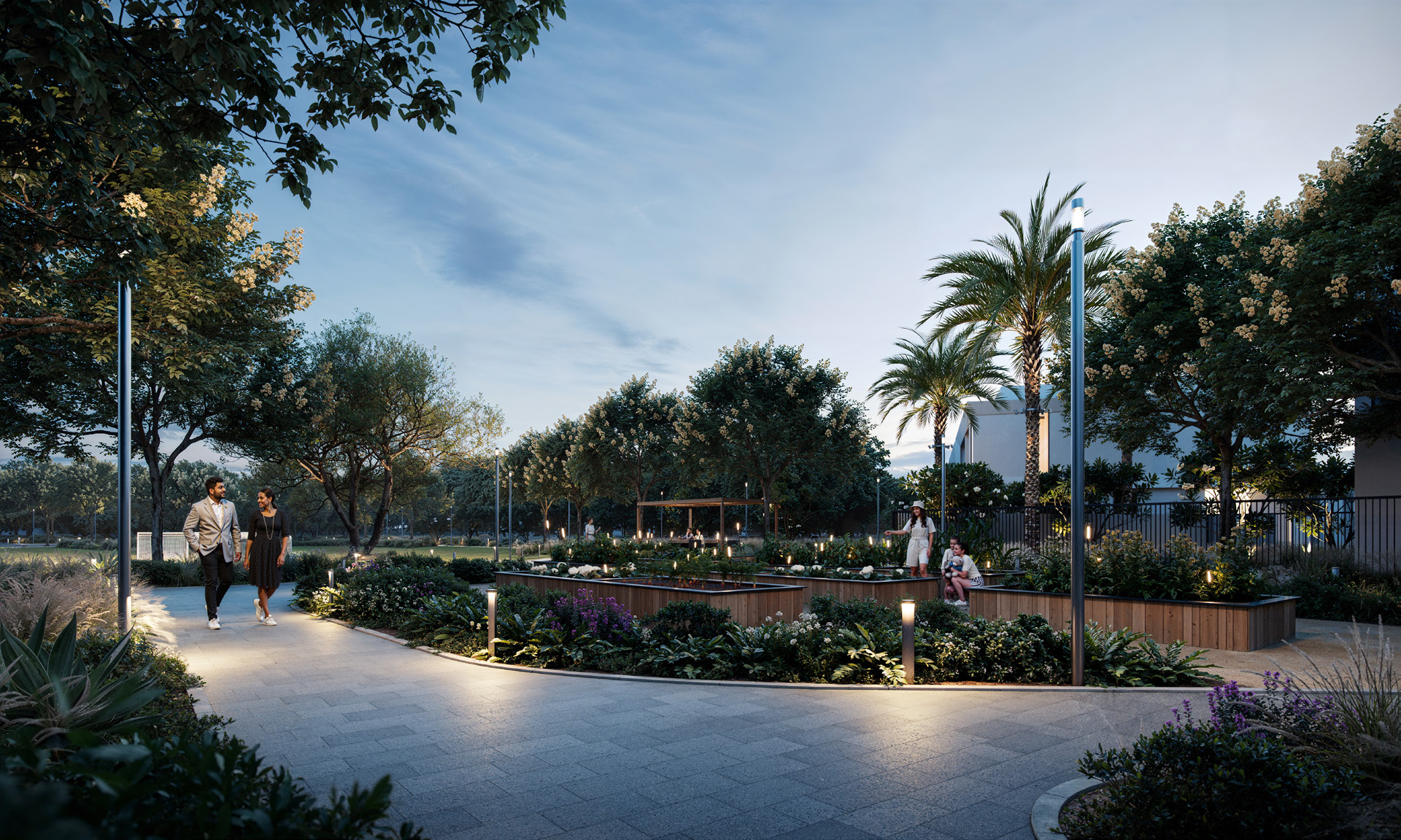 A well-lit pedestrian walkway in a lush green community garden at Greenspoint, Emaar South, with people enjoying an evening stroll.3 & 4 Bedroom Townhouses at Greenspoint, Emaar South