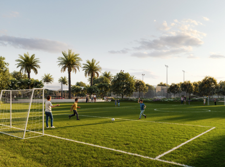 A lush green football field with children playing under the open sky at Greenspoint, Emaar South3 & 4 Bedroom Townhouses at Greenspoint, Emaar South.